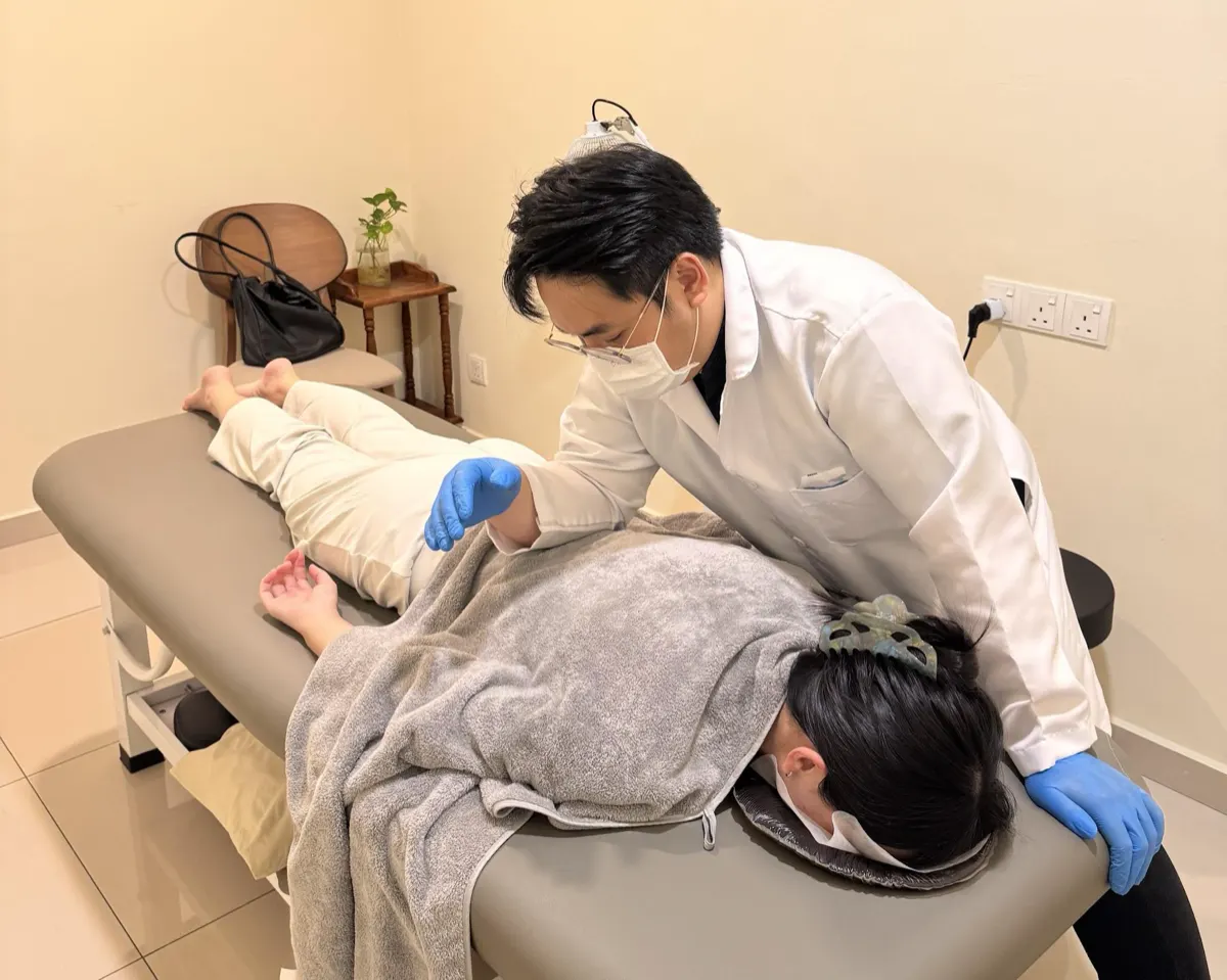 中医师为俯卧的患者进行推拿治疗